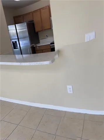 Kitchen with sink, light tile patterned floors, and stainless steel fridge with ice dispenser