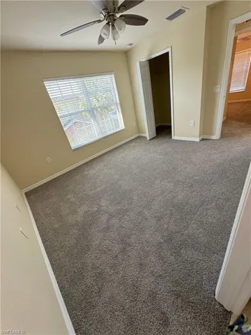 Carpeted empty room featuring ceiling fan