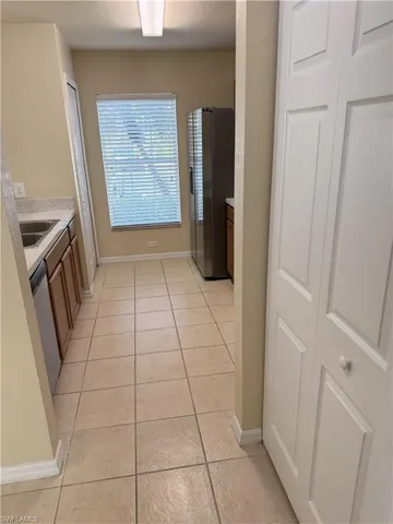 Kitchen with stainless steel appliances, sink, a textured ceiling, and light tile patterned floors