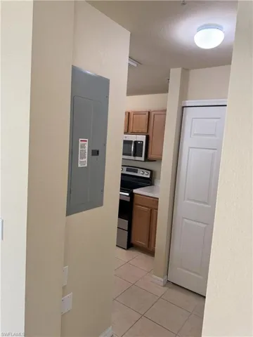 Kitchen with light tile patterned floors, electric panel, and appliances with stainless steel finishes