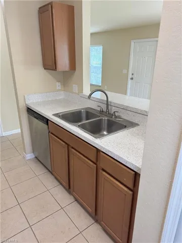 Kitchen with dishwasher, sink, light tile patterned flooring, and kitchen peninsula