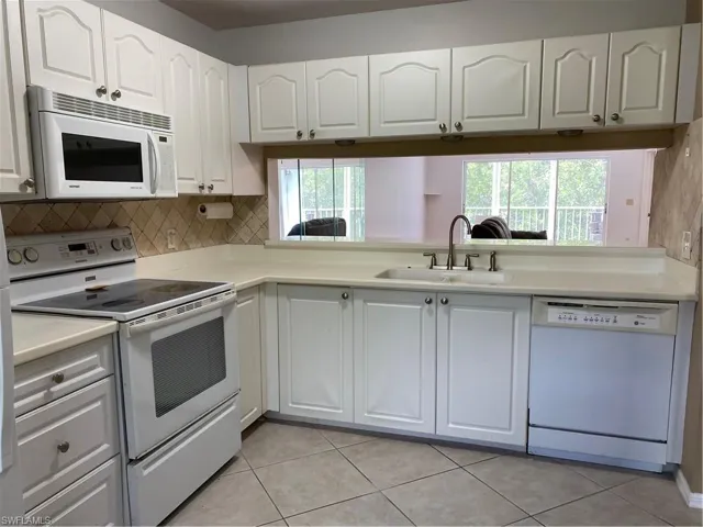 Kitchen with tasteful backsplash, range, dishwashing machine, white cabinetry, and a sink