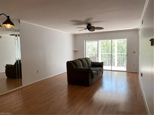 Living area featuring a ceiling fan, crown molding, baseboards, and wood finished floors