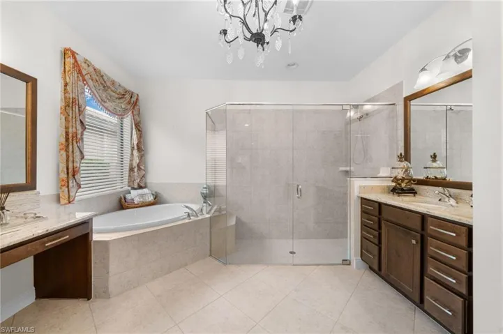 Bathroom with vanity, tile patterned flooring, plus walk in shower, and a chandelier