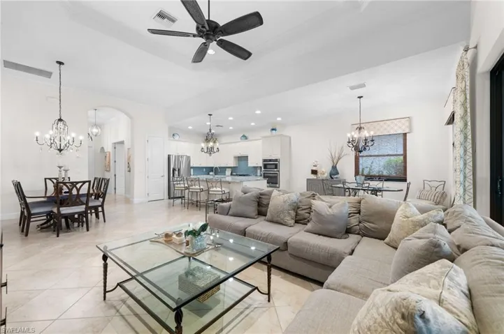 Living room with ornamental molding, a tray ceiling, ceiling fan, sink, and light tile patterned floors