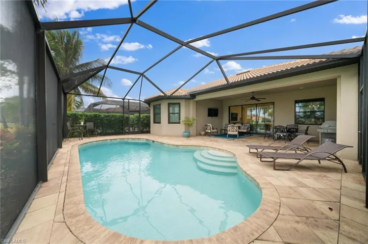 View of pool with a lanai, outdoor lounge area, ceiling fan, and a patio