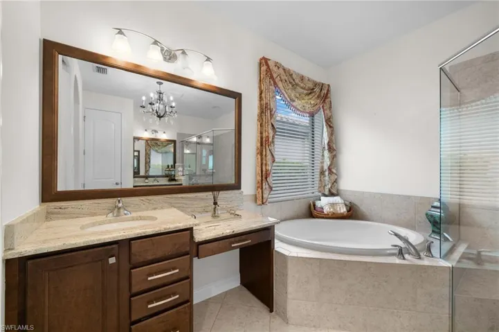 Bathroom with tile patterned flooring, vanity, separate shower and tub, and a notable chandelier