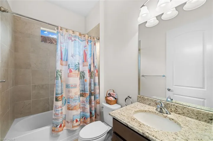 Full bathroom featuring vanity, toilet, and shower / bathtub combination with curtain