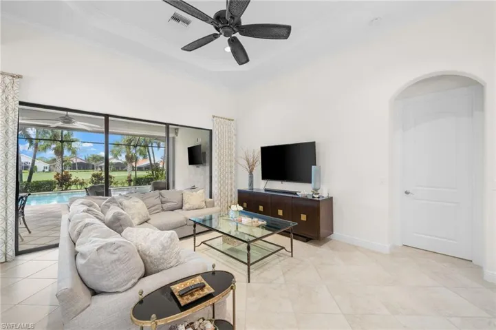 Living room with a raised ceiling, ceiling fan, and ornamental molding