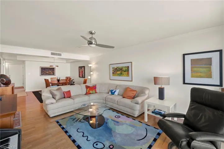 Living room featuring wood finished floors, ornamental molding, and ceiling fan