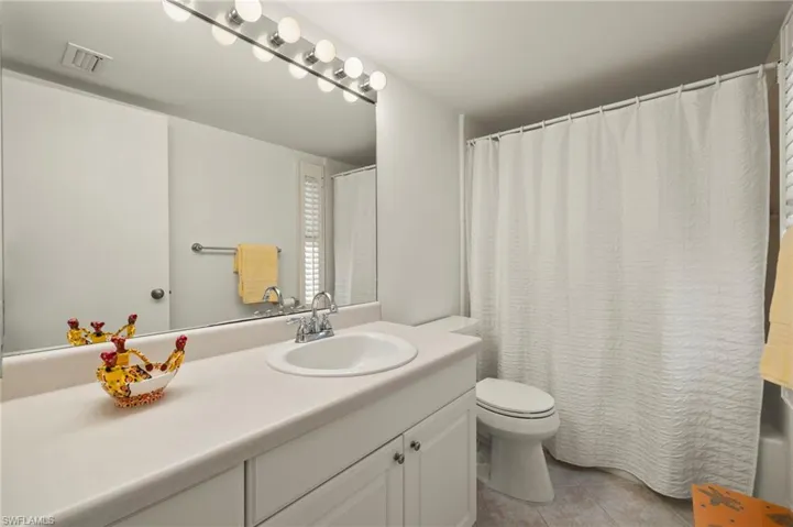 Bathroom featuring vanity, curtained shower, and light tile patterned flooring
