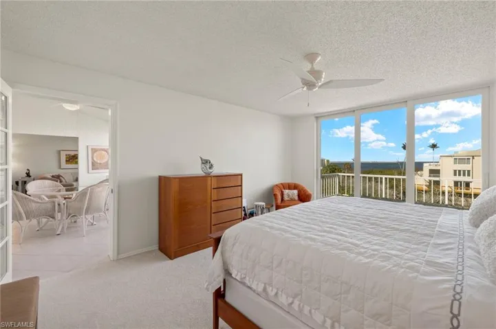 Bedroom with floor to ceiling windows, a textured ceiling, a ceiling fan, access to exterior, and carpet floors