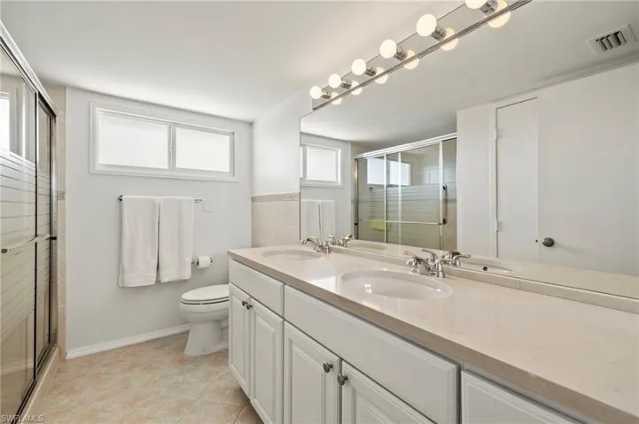 Bathroom with double vanity, a stall shower, and light tile patterned floors