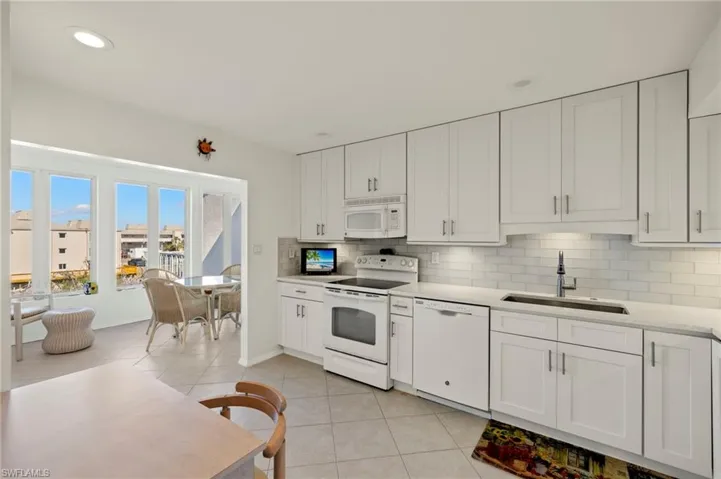 Kitchen with white appliances, white cabinetry, tasteful backsplash, recessed lighting, and light tile patterned flooring