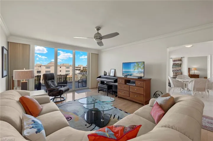 Living room featuring ornamental molding, wood finished floors, expansive windows, and a ceiling fan