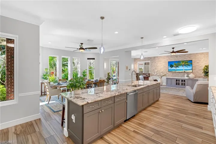 Kitchen with light wood-style floors, open floor plan, gray cabinets, a ceiling fan, and ornamental molding