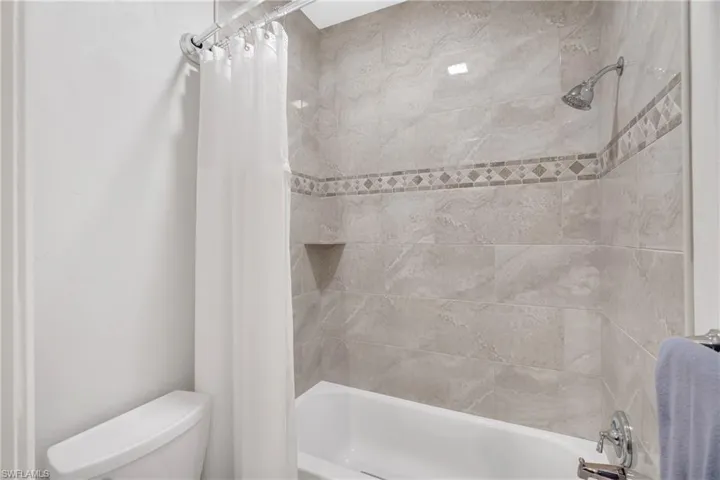 Bathroom with shower / bath combination with curtain and toilet