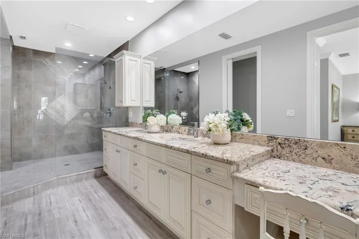 Full bathroom featuring a walk in shower, double vanity, light wood finished floors, and recessed lighting
