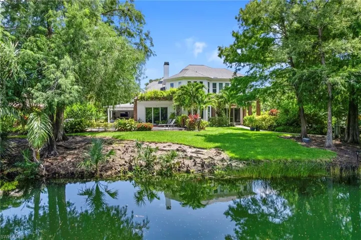 Back of property with a lawn, a chimney, and a water view