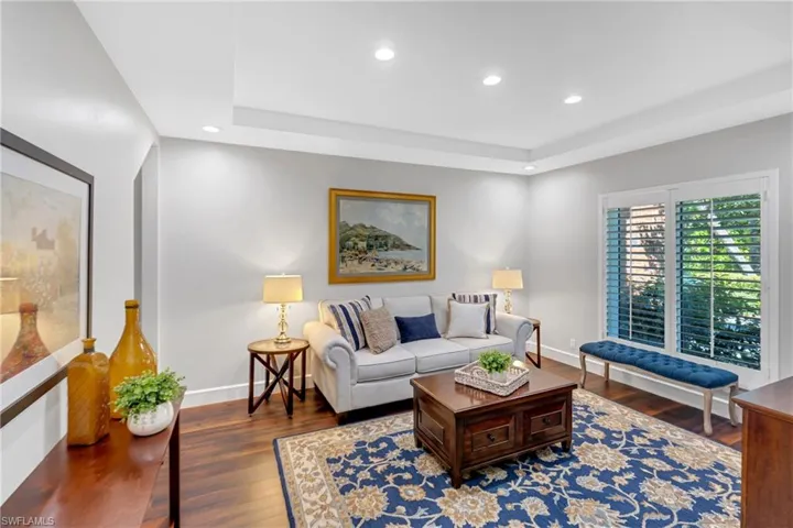 Living room featuring recessed lighting, dark wood-type flooring, and a raised ceiling