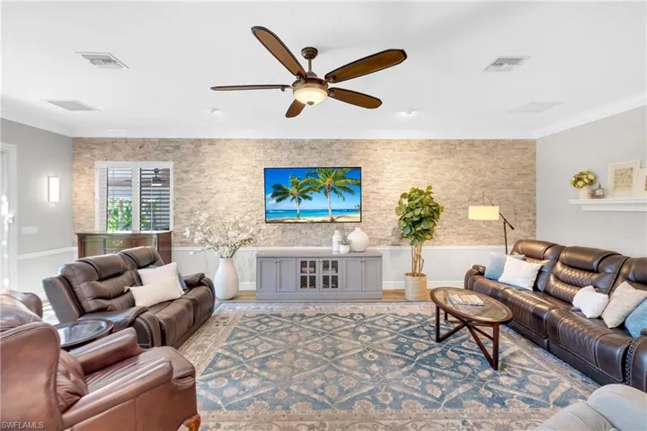 Living room featuring crown molding, wood finished floors, and a ceiling fan