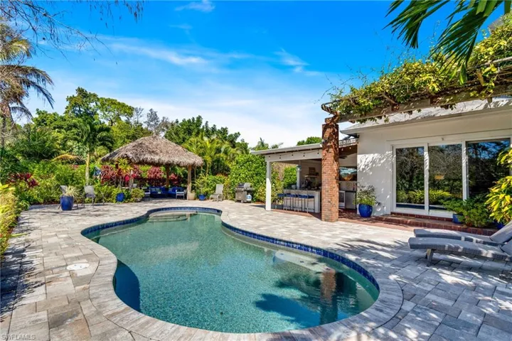 Swimming pool featuring a gazebo, a bar, a patio, and a grill
