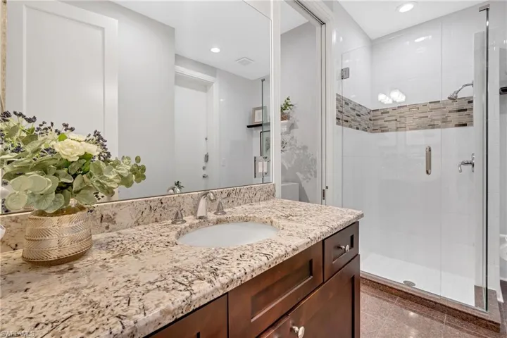 Full bath featuring a shower stall, vanity, recessed lighting, and granite floors