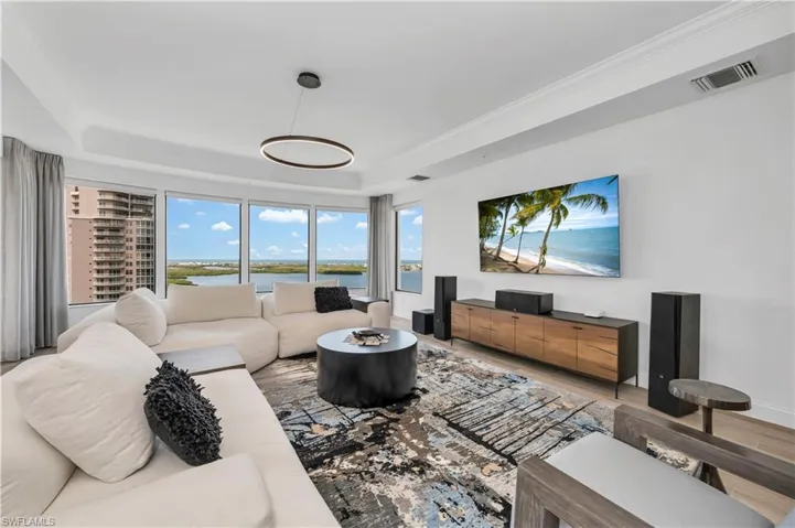 Living room featuring hardwood / wood-style flooring, a water view, and a raised ceiling