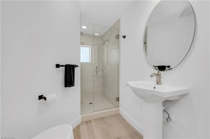 Bath 3 with a shower with door, hardwood / wood-style flooring, and toilet