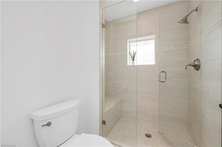 Bath featuring a shower with shower door and toilet