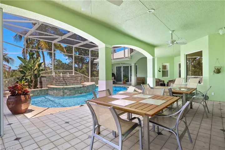 View of swimming pool featuring an in ground hot tub, ceiling fan, glass enclosure, and a patio