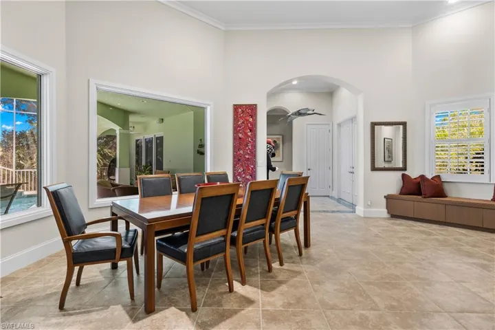 Dining area with a towering ceiling, ornamental molding, light tile patterned flooring, and ceiling fan