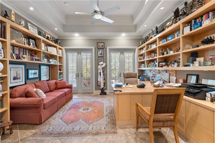 Office with built in desk, ceiling fan, a raised ceiling, and ornamental molding