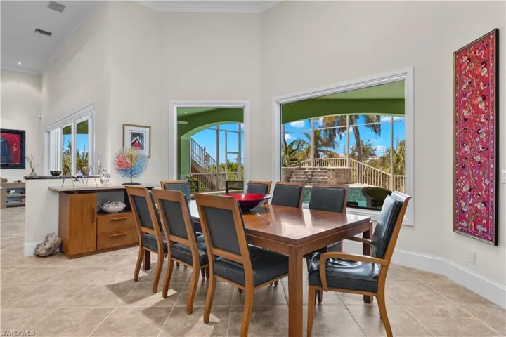 Tiled dining space with a healthy amount of sunlight, ornamental molding, and a towering ceiling