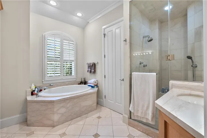 Bathroom with vanity, tile patterned floors, ornamental molding, and shower with separate bathtub
