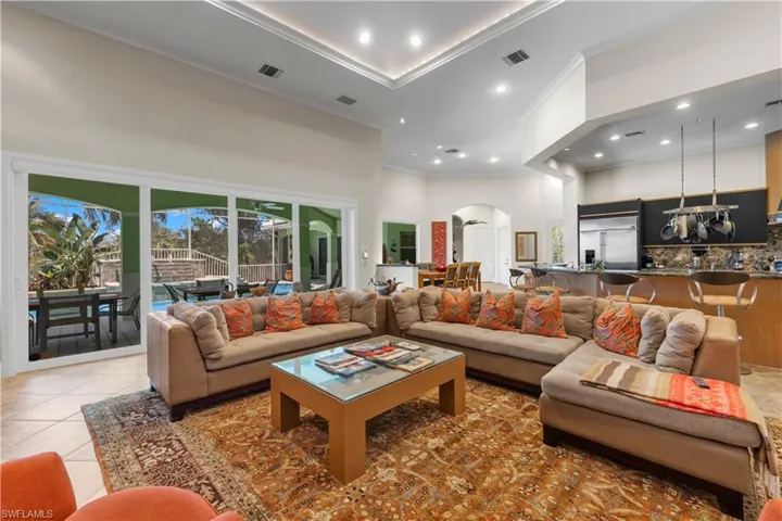 Tiled living room with crown molding, a chandelier, and a high ceiling