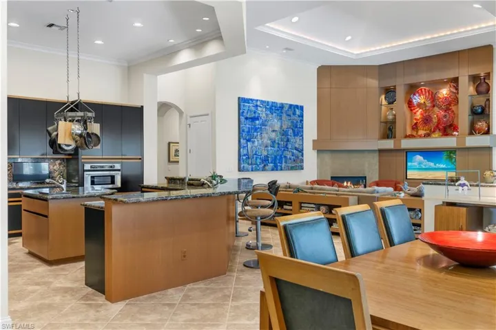 Kitchen with stainless steel oven, a kitchen island, dark stone counters, light tile patterned flooring, and pendant lighting