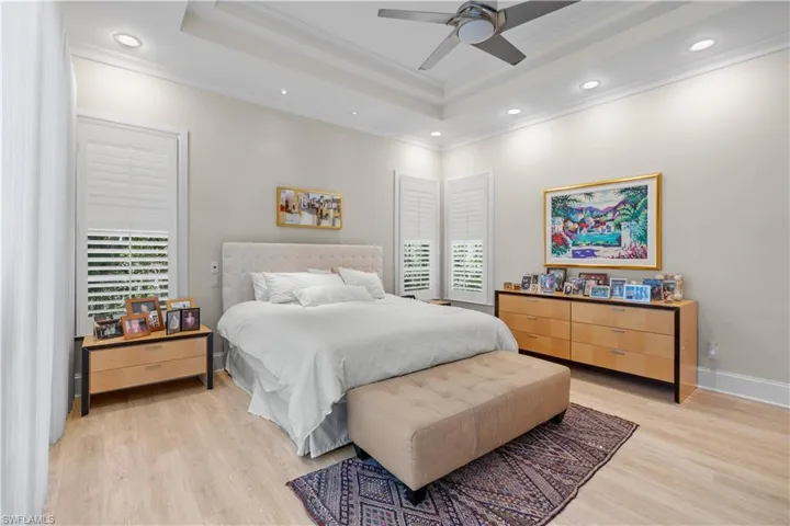 Bedroom featuring ceiling fan, multiple windows, and light wood-type flooring