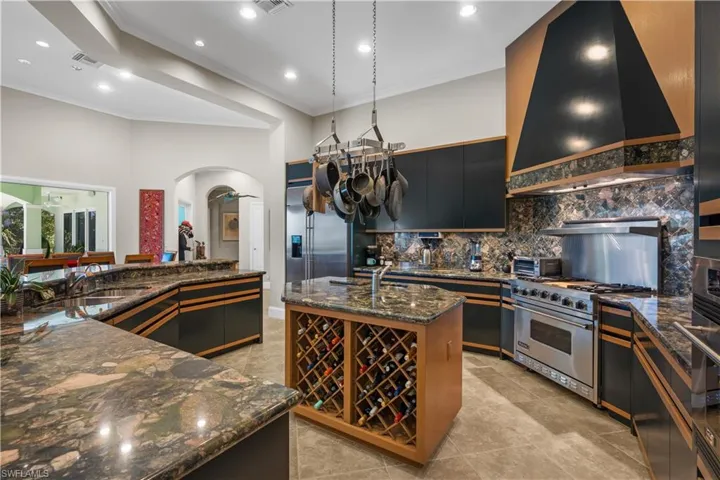 Kitchen featuring premium appliances, sink, hanging light fixtures, custom exhaust hood, and a center island with sink