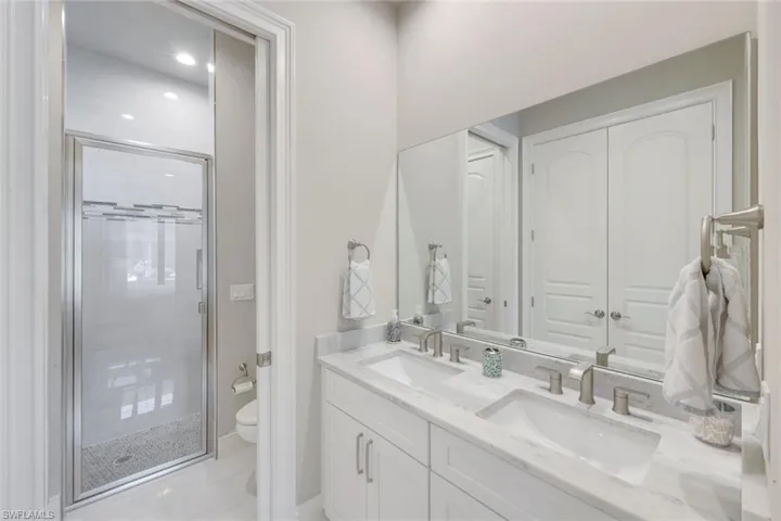 Bathroom with double vanity, a stall shower, and recessed lighting