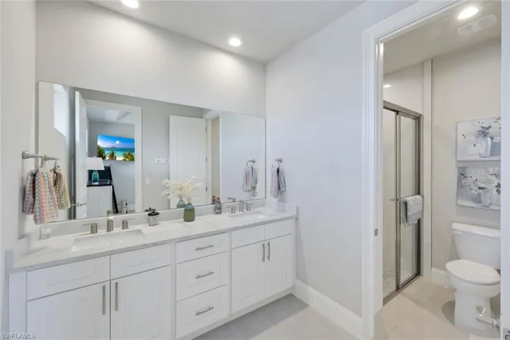 Full bath with double vanity, a shower stall, and recessed lighting