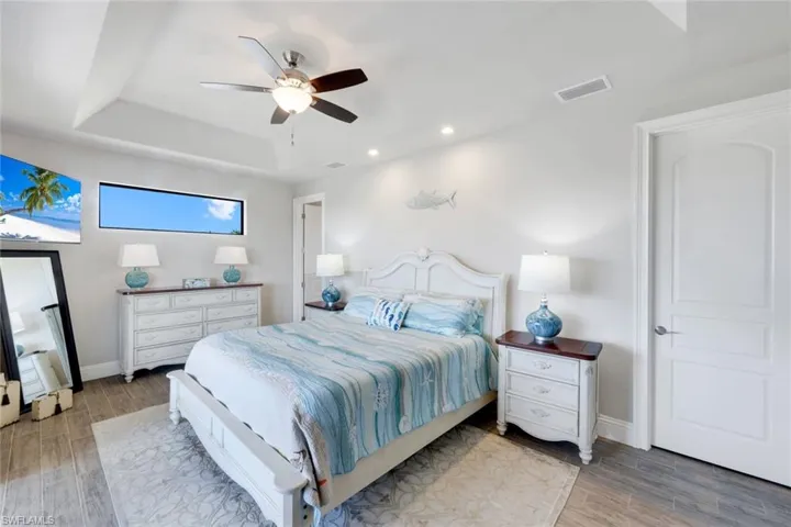 Bedroom with wood tiled floors, a ceiling fan, recessed lighting, and a raised ceiling
