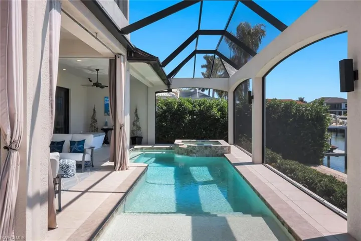 Integrated pool / hot tub featuring a sunroom, a patio, glass enclosure, and a water view