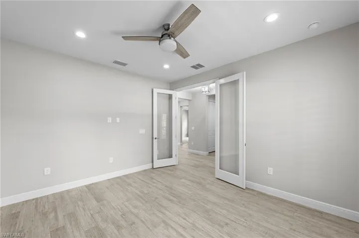 Spacious room featuring light wood-finish flooring, recessed lighting, and a contemporary ceiling fan