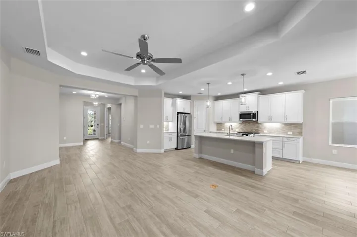 Expansive living area featuring wood-finish flooring, recessed lighting, and a tray ceiling with a ceiling fan