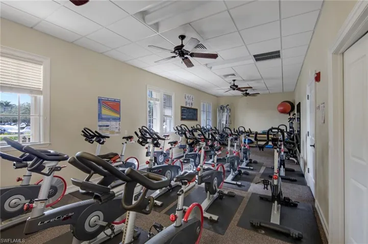 Fitness room featuring multiple stationary bikes, neutral wall paint, white trim, and ceiling fans