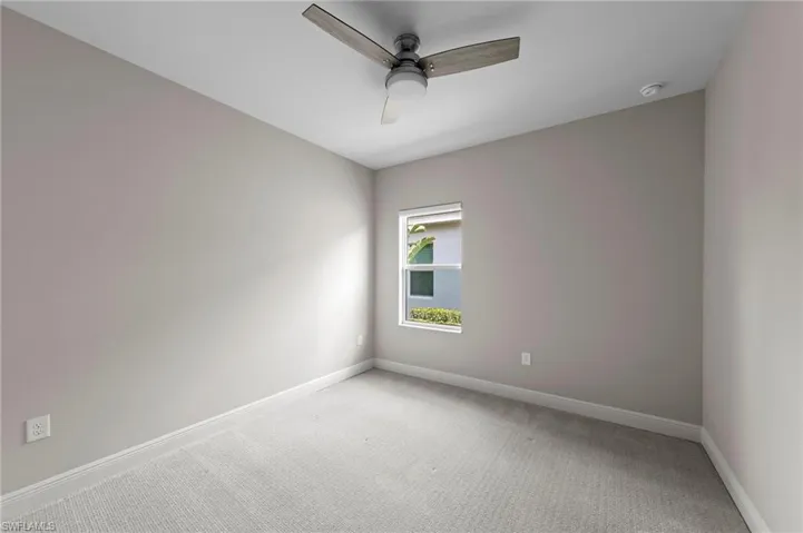 Carpeted interior room with neutral wall tones and a ceiling fan with integrated lighting