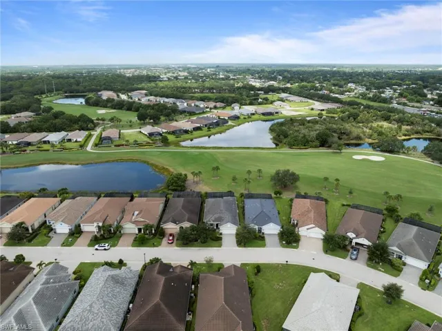 Aerial perspective of a residential community featuring numerous single-story homes, a golf course, and multiple water features