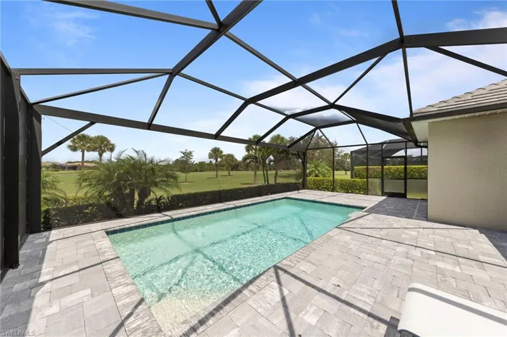 Screened-in outdoor living area featuring a rectangular pool, paver decking, and a golf course backdrop