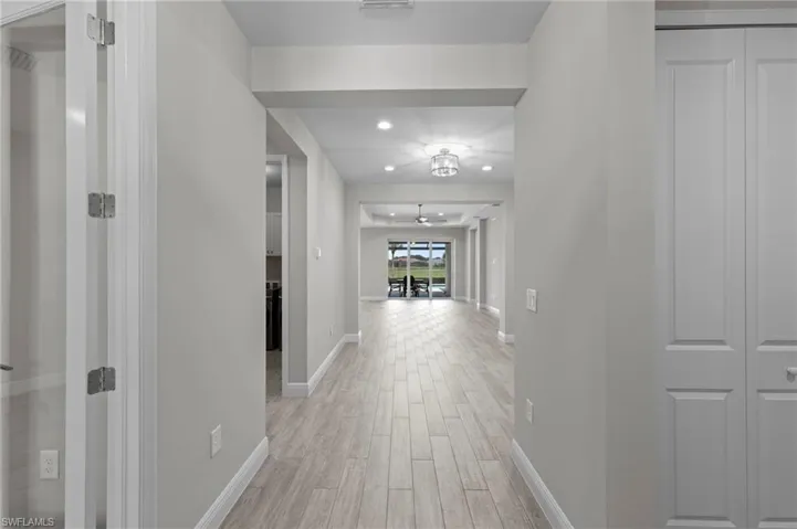 Long hallway featuring light wood-finish flooring, recessed lighting, and a ceiling fan
